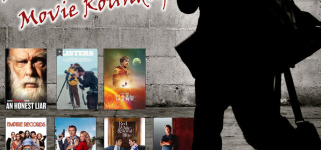 Man walking in front of a wall with movie posters on it.